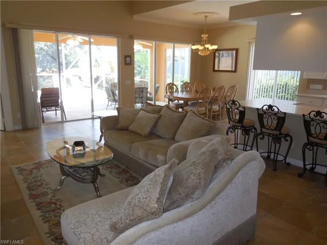 Tiled living room featuring plenty of natural light, crown molding, and an inviting chandelier