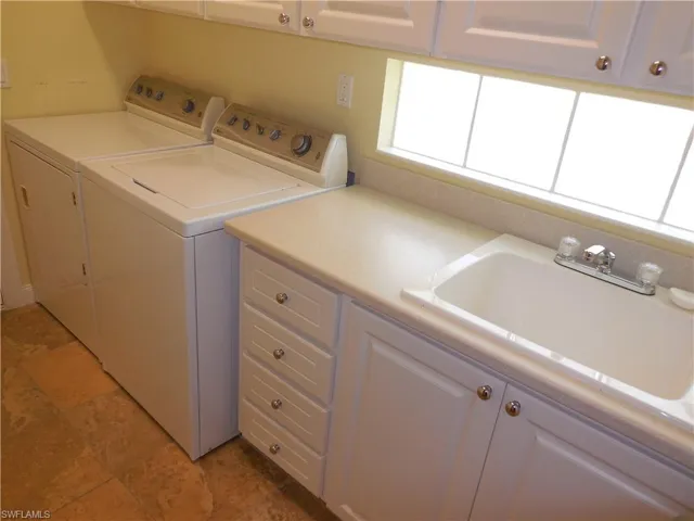 Washroom with sink, cabinets, washer and clothes dryer, and light tile patterned floors