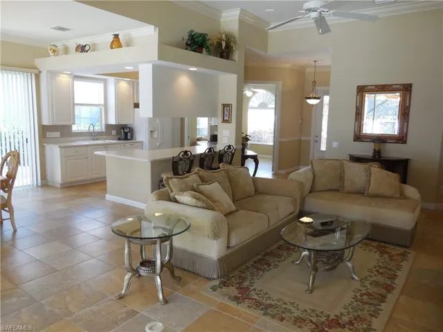 Living room featuring sink, ornamental molding, light tile patterned floors, and ceiling fan