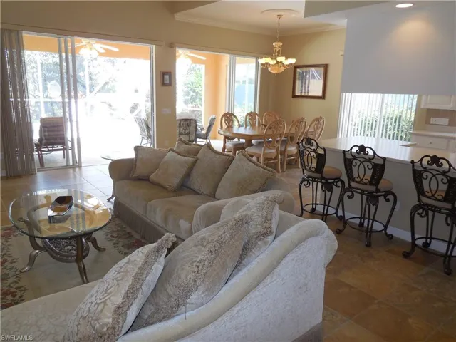 Tiled living room with a healthy amount of sunlight, crown molding, and ceiling fan with notable chandelier