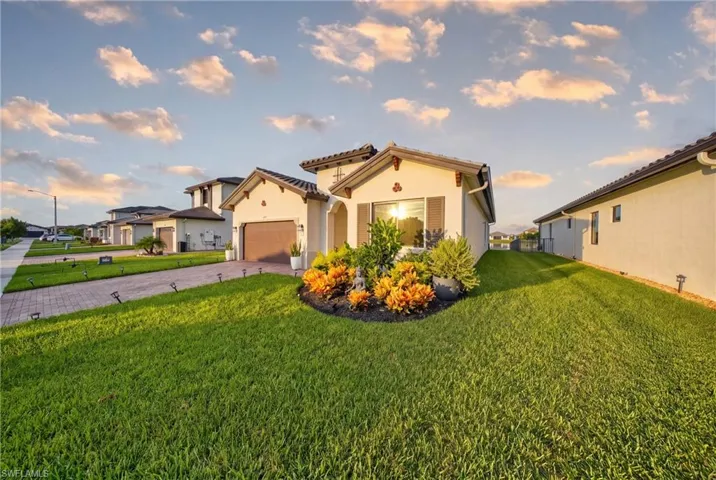 Mediterranean-inspired exterior with a tiled roof, stucco finish, decorative shutters, and a professionally landscaped front yard