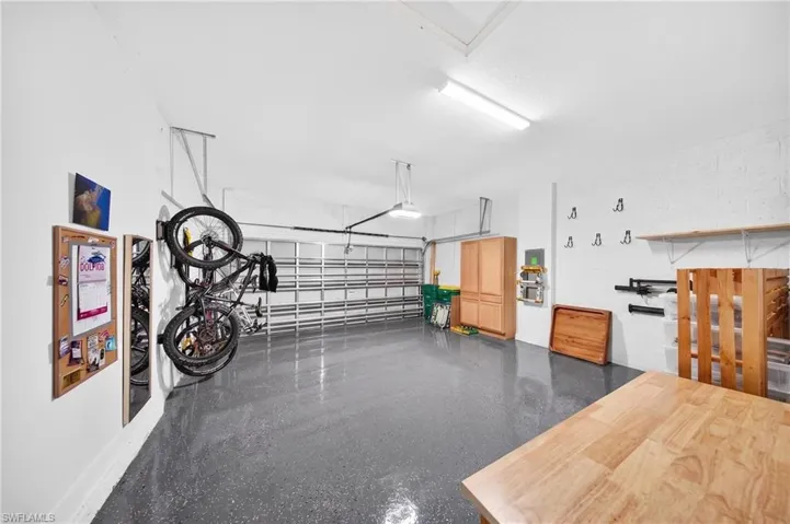 Attached garage with grey epoxy flooring, built-in shelving, and overhead lighting