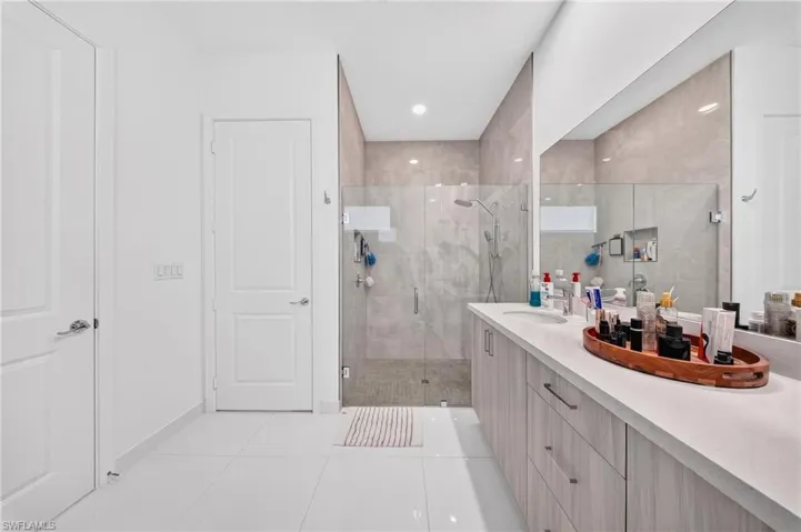 Spacious bathroom featuring an expansive single vanity with a white countertop, wood-finish cabinetry, and an integrated rectangular sink