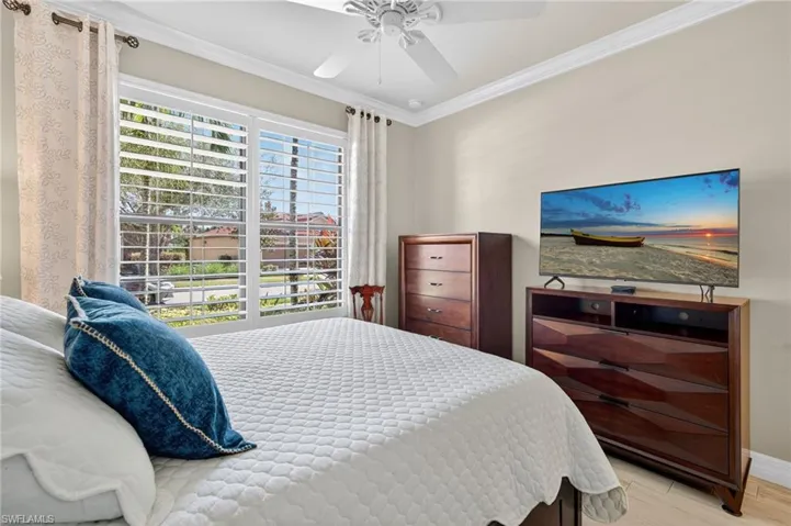 Bedroom with crown molding, light wood-type flooring, and ceiling fan