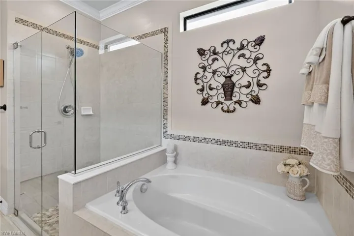 Full bathroom featuring a garden tub, a stall shower, and ornamental molding