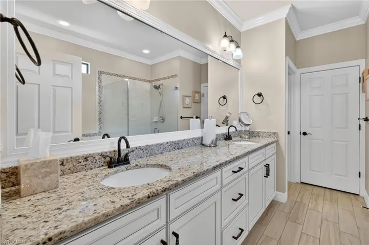Full bathroom featuring a stall shower, double vanity, and ornamental molding