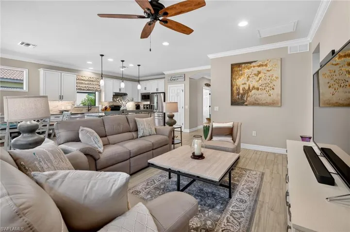 Living room with recessed lighting, crown molding, arched walkways, light wood-type flooring, and a ceiling fan