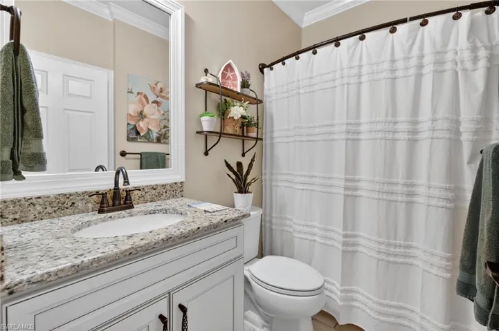 Full bath featuring a shower with shower curtain, vanity, and ornamental molding