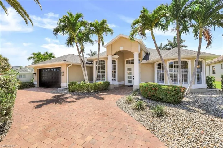 The front of the home is lavishly landscaped with rock + block paving + established trees + shrubs