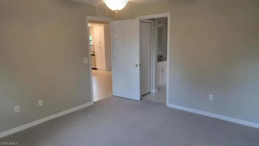 Unfurnished bedroom with baseboards and light colored carpet