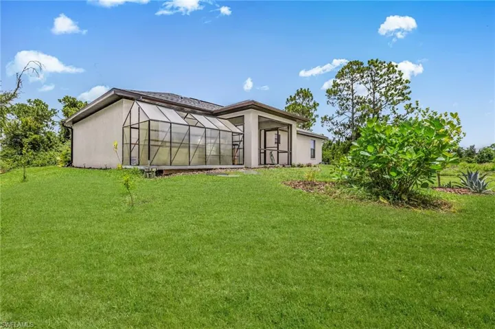 Rear view of house featuring a lawn and stucco siding