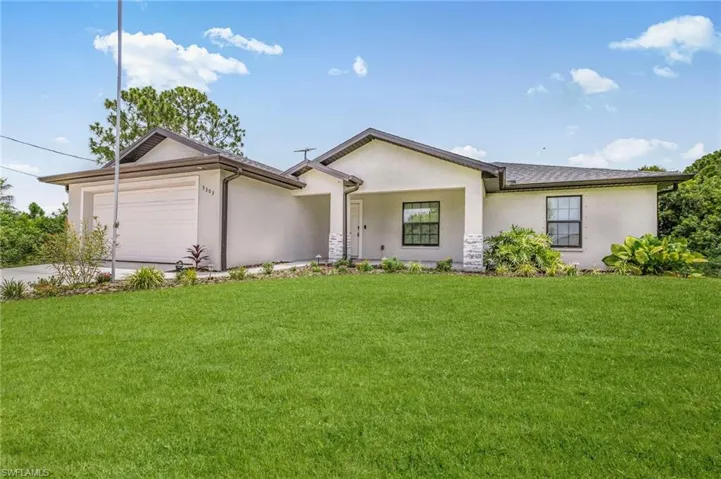Ranch-style home featuring stucco siding, an attached garage, a front lawn, and concrete driveway