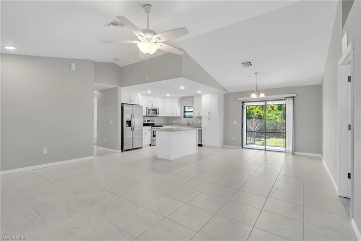 Unfurnished living room with visible vents, lofted ceiling, marble finish floor, a ceiling fan, and baseboards