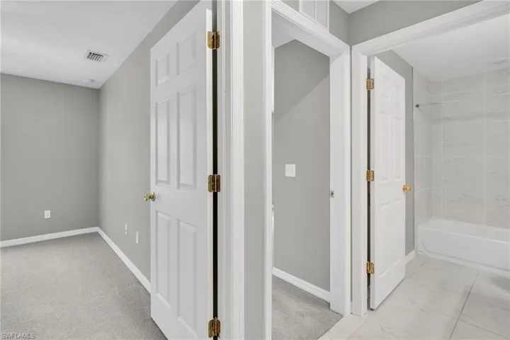 Hallway featuring visible vents, marble finish floor, and baseboards