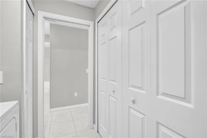 Corridor with washer and dryer, baseboards, and marble finish floor