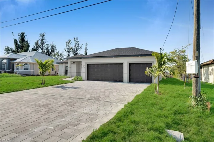 Ranch-style home featuring decorative driveway, a front lawn, a garage, and stucco siding