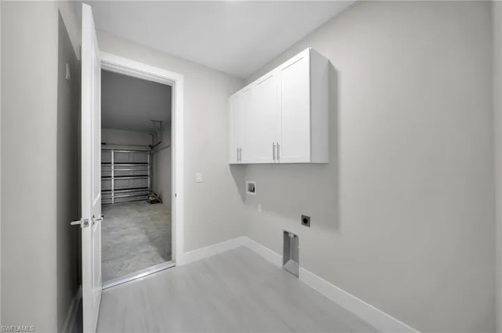 Washroom featuring hookup for an electric dryer, cabinet space, and baseboards