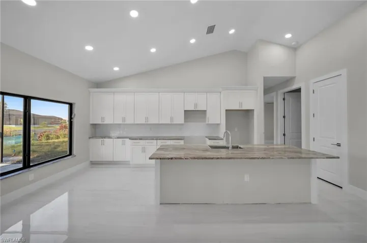Kitchen featuring a sink, a center island with sink, white cabinets, high vaulted ceiling, and recessed lighting