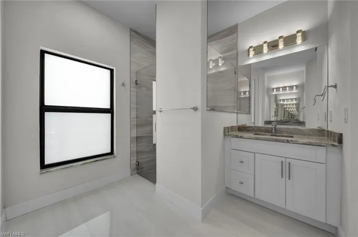 Bathroom with a tile shower, vanity, and baseboards