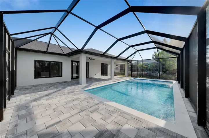 Outdoor pool featuring a patio area, a ceiling fan, and glass enclosure