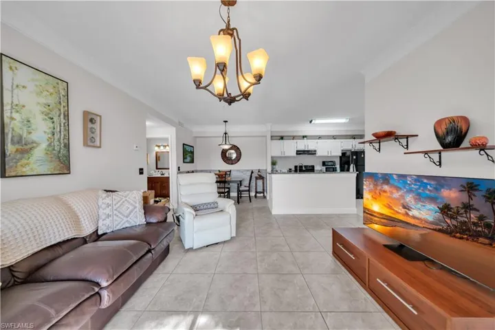 Living area with ornamental molding, a chandelier, and light tile patterned flooring