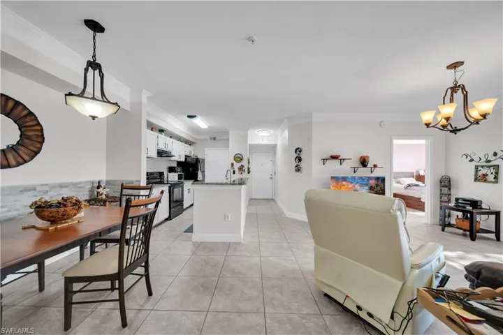 Dining space with crown molding, light tile patterned flooring, and suspended lighting