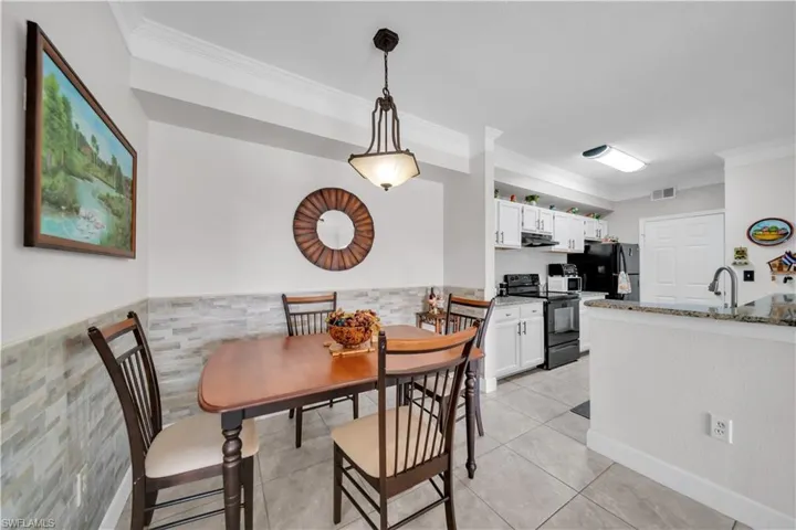Dining room featuring a wainscoted wall, crown molding, light tile patterned floors, and tile walls