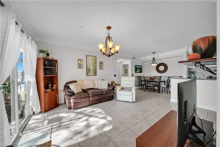 Living room featuring ornamental molding, light tile patterned floors, and hanging lights