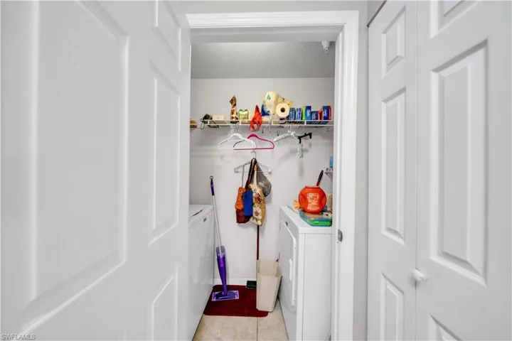 Laundry area with washing machine and clothes dryer, a textured ceiling, and light tile patterned floors