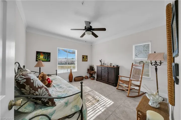Bedroom with a ceiling fan, crown molding, and light tile patterned floors