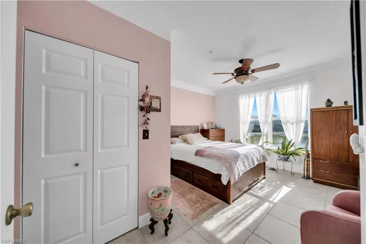 Bedroom featuring ornamental molding, ceiling fan, light tile patterned floors, and a closet
