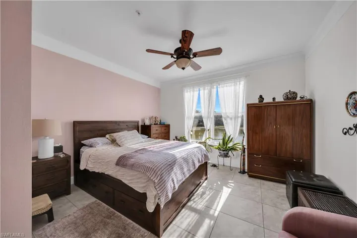 Bedroom featuring light tile patterned flooring, crown molding, and ceiling fan