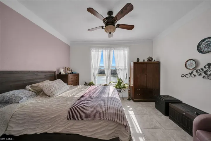 Bedroom featuring ornamental molding, ceiling fan, a water view, and light tile patterned floors