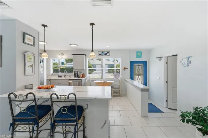 Kitchen with a kitchen breakfast bar, plenty of natural light, and light stone countertops