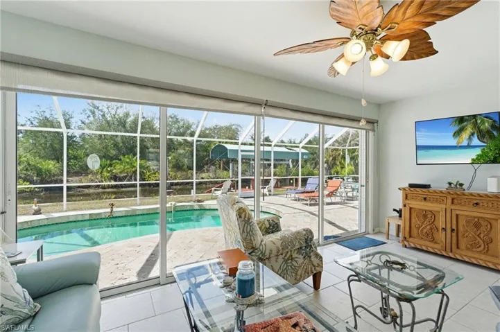 Living room with a sunroom, ceiling fan, and light tile patterned flooring