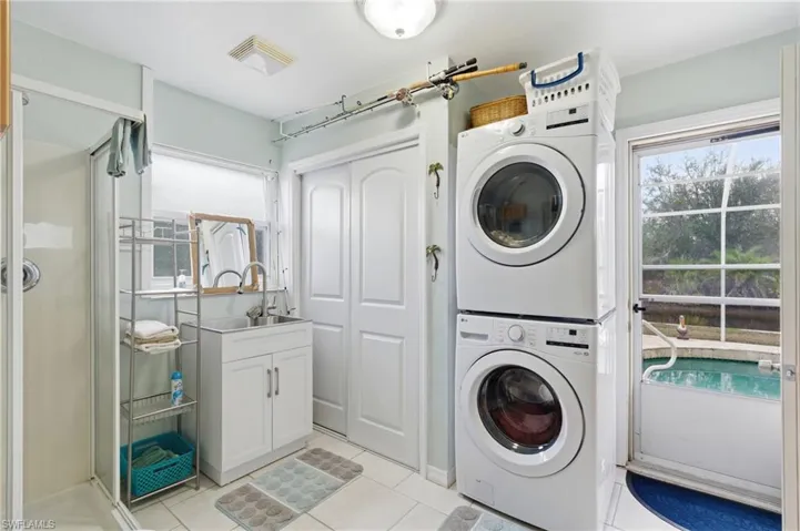 Laundry area with stacked washer / dryer and light tile patterned floors