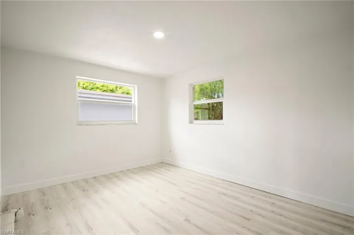 Unfurnished room featuring wood finished floors, plenty of natural light, and recessed lighting
