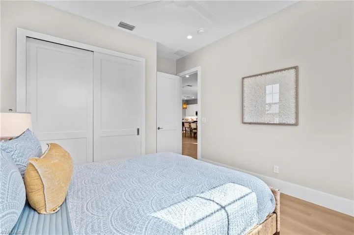 Bedroom featuring wood finished floors, a closet, ceiling fan, baseboards, and visible vents. virtually edited photo