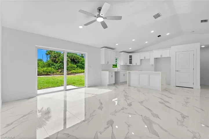 Kitchen featuring recessed lighting, white cabinets, a center island, light countertops, and open floor plan