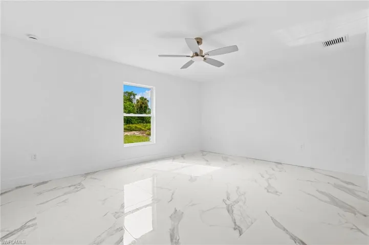 Spare room with a ceiling fan and light marble finish flooring