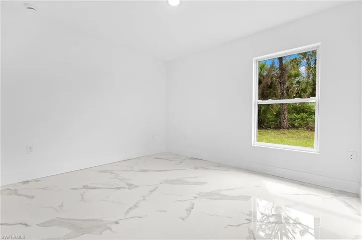 Unfurnished room featuring baseboards and light marble finish floors