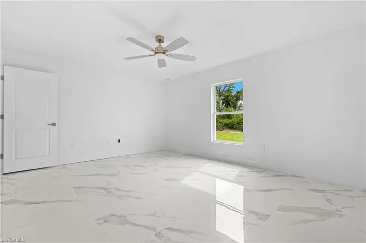 Empty room featuring light marble finish floors and ceiling fan