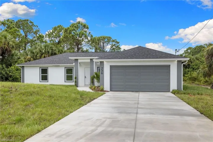 Ranch-style home featuring stucco siding, an attached garage, a front lawn, and concrete driveway