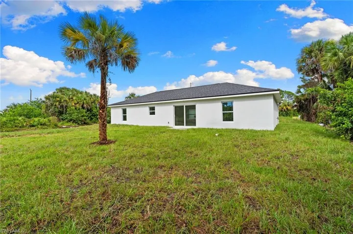 Rear view of house with a lawn and stucco siding