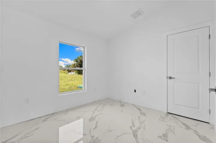 Spare room featuring lofted ceiling and light marble finish floors