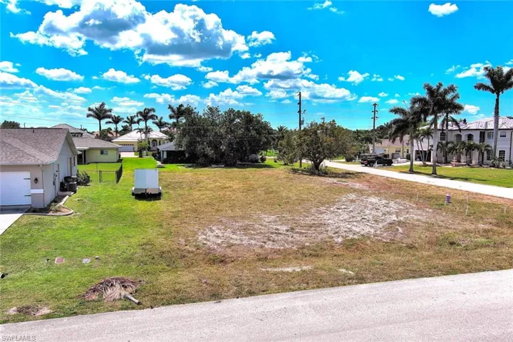 View of grassy yard with driveway and a residential view