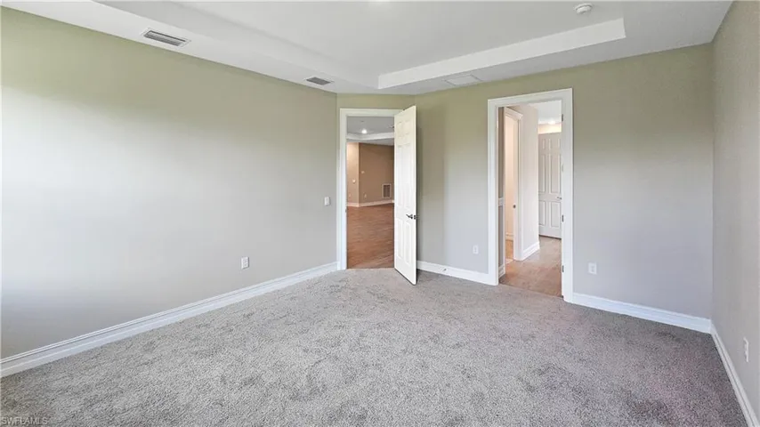 Unfurnished bedroom with a raised ceiling and carpet floors