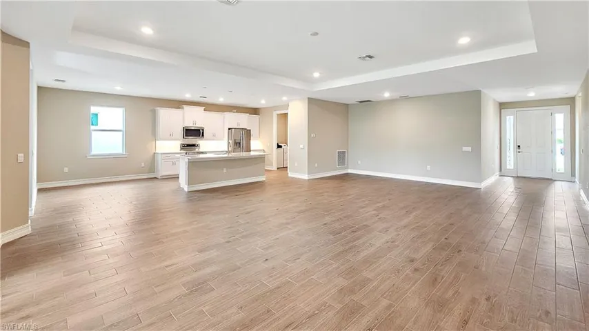 Unfurnished living room with light wood-type flooring and a tray ceiling