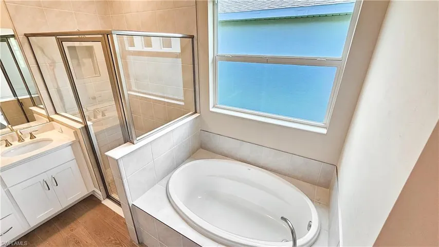 Bathroom with vanity, shower with separate bathtub, and hardwood / wood-style floors