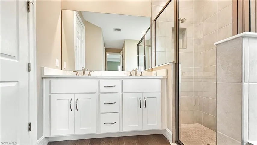 Bathroom with double vanity, an enclosed shower, and hardwood / wood-style floors